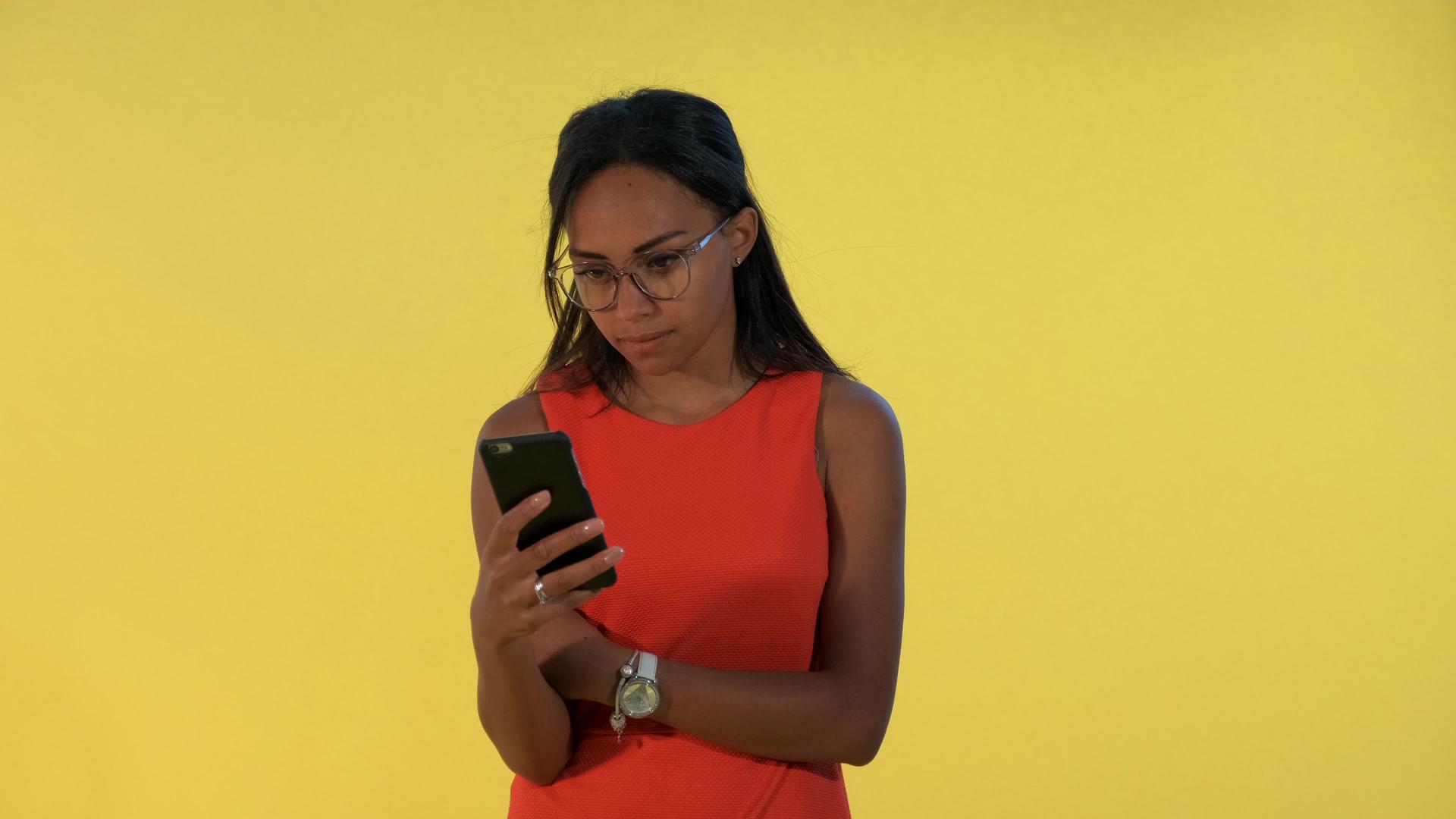 多种族美女对黄色背景的智能手机感到惊讶笑了起来视频的预览图