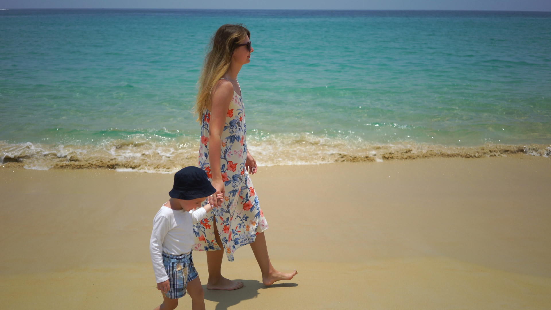 母亲和儿子沿着海滩步行视频的预览图