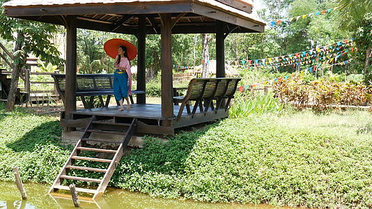 4K美丽的泰国女人穿着泰国传统服装带着红色的雨伞走在河边视频的预览图