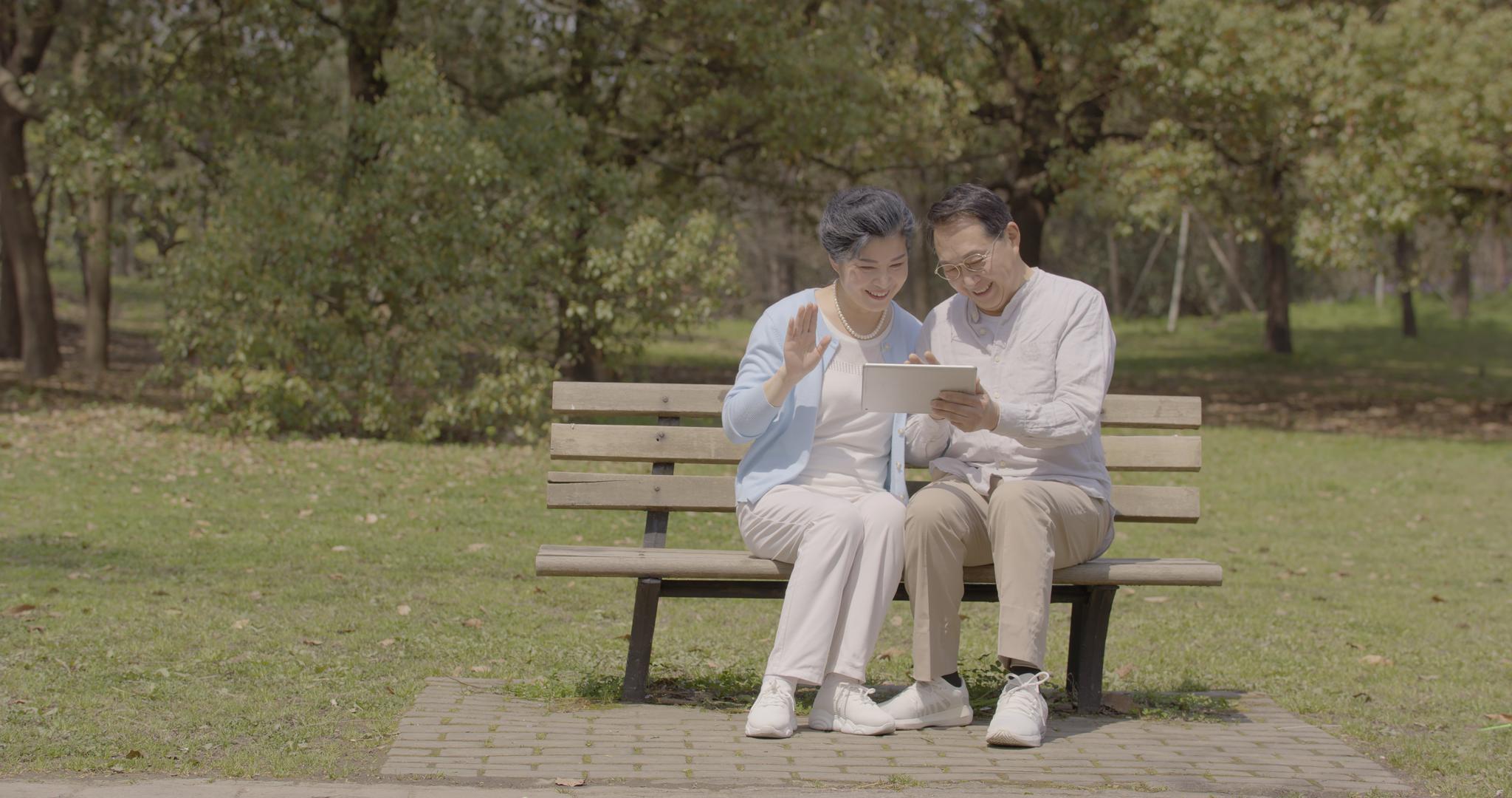 老年夫妇公园长椅上使用平板电脑视频的预览图