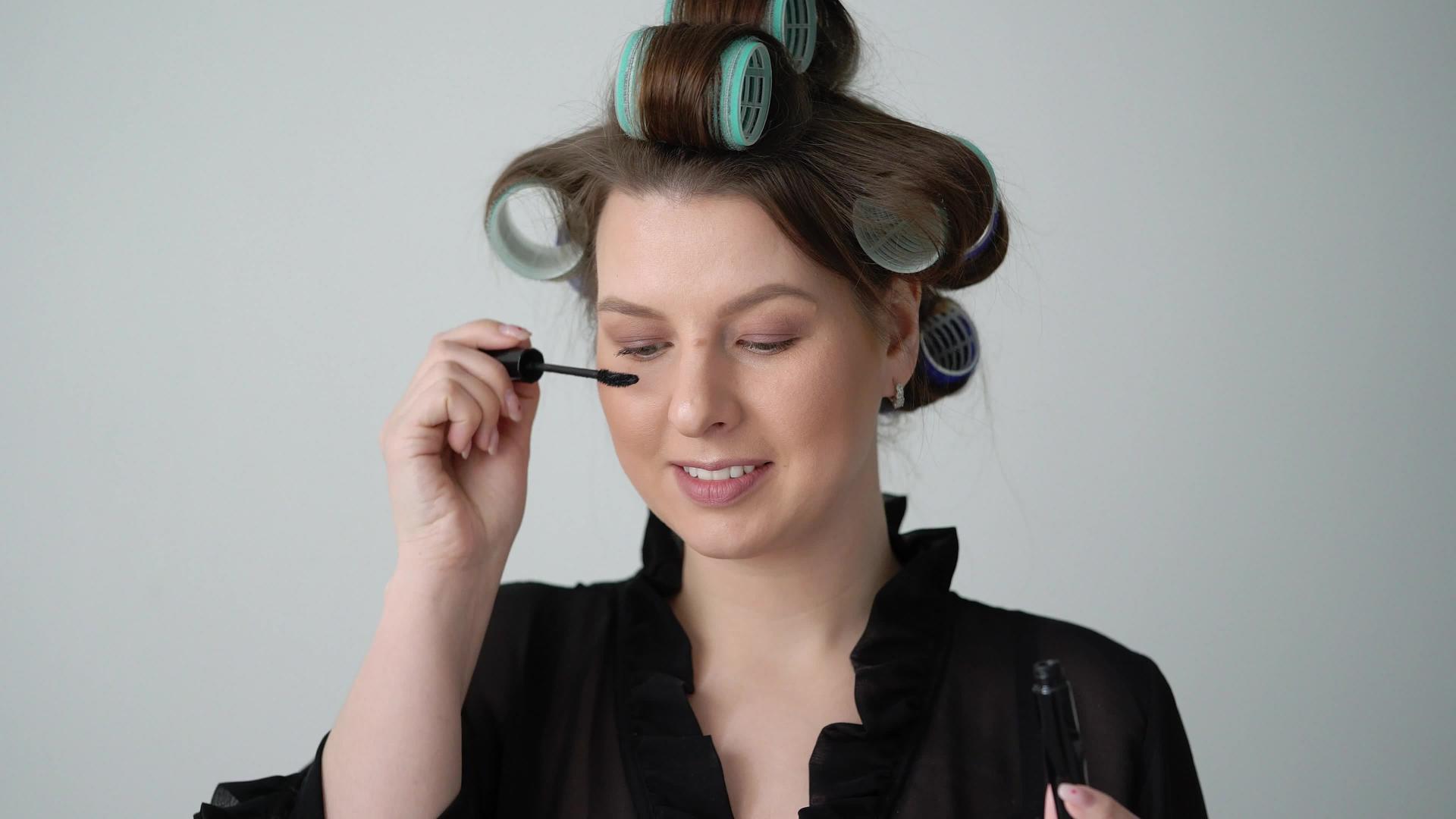 头发上有卷发的女孩用马斯卡拉做化妆品视频的预览图