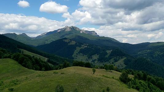 罗曼尼亚喀尔巴阡山脉的云层在岩石山脉牧场和绿色森林上移动视频的预览图