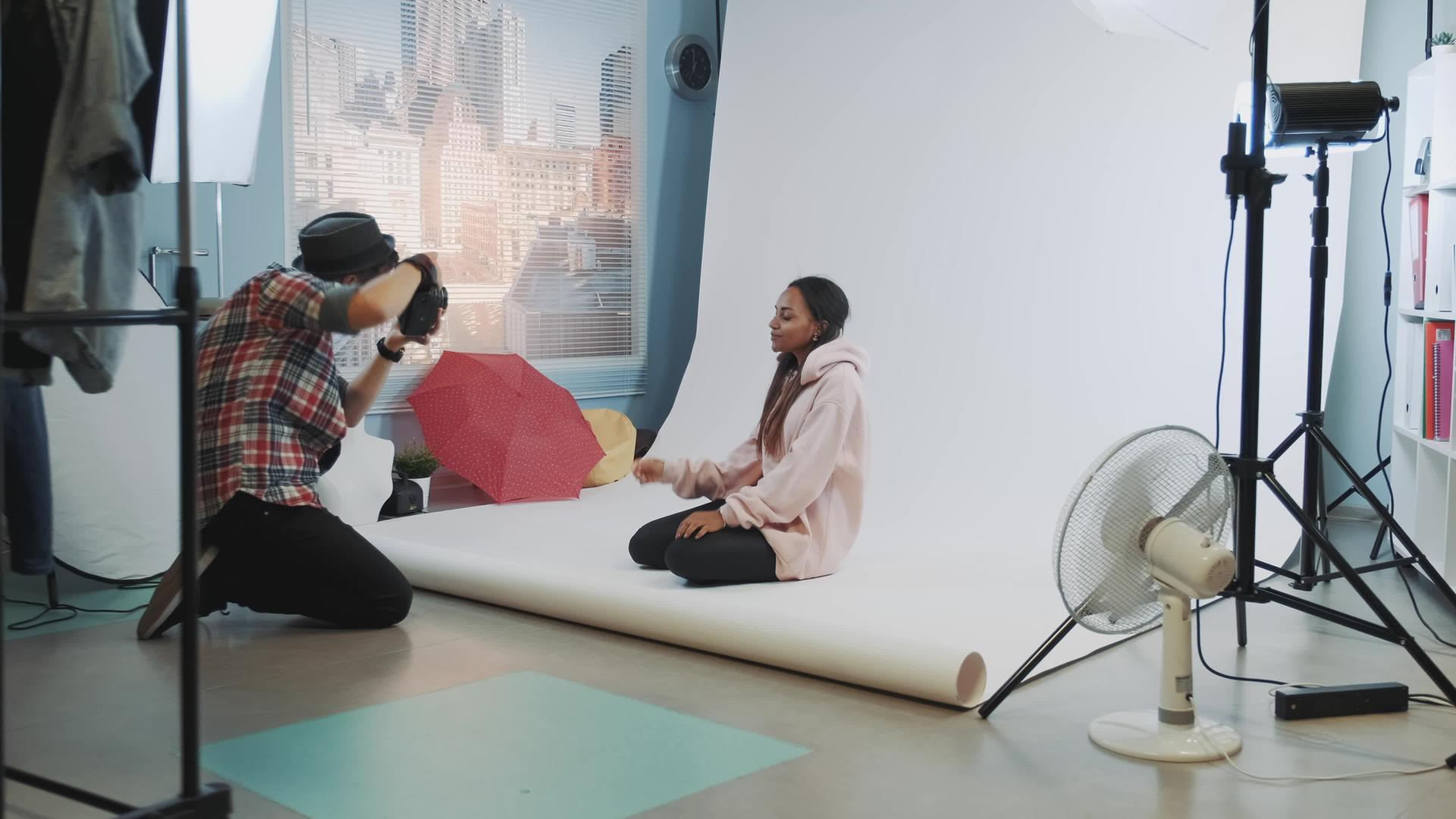 年轻的高加索摄影师在工作室拍照时坐在地板上视频的预览图