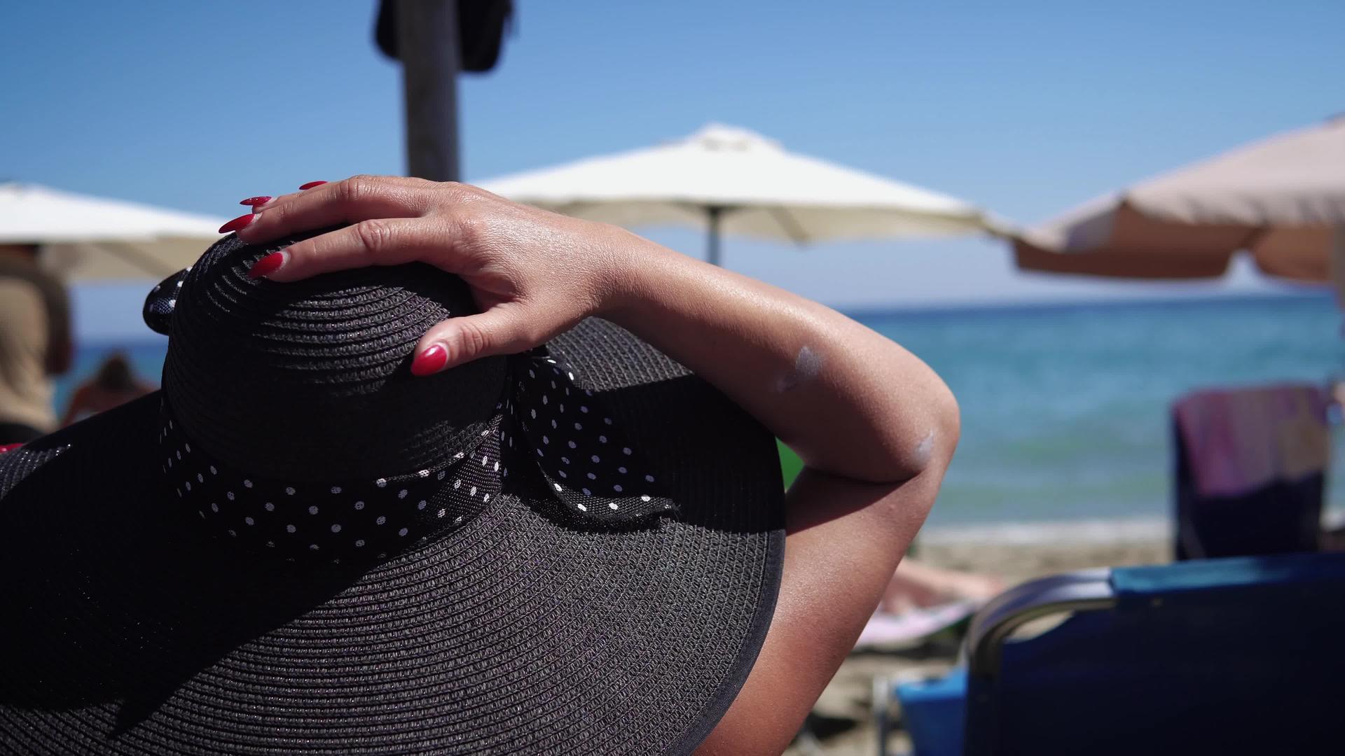 穿着帽子和红指甲的性感美女在沙滩上放松视频的预览图