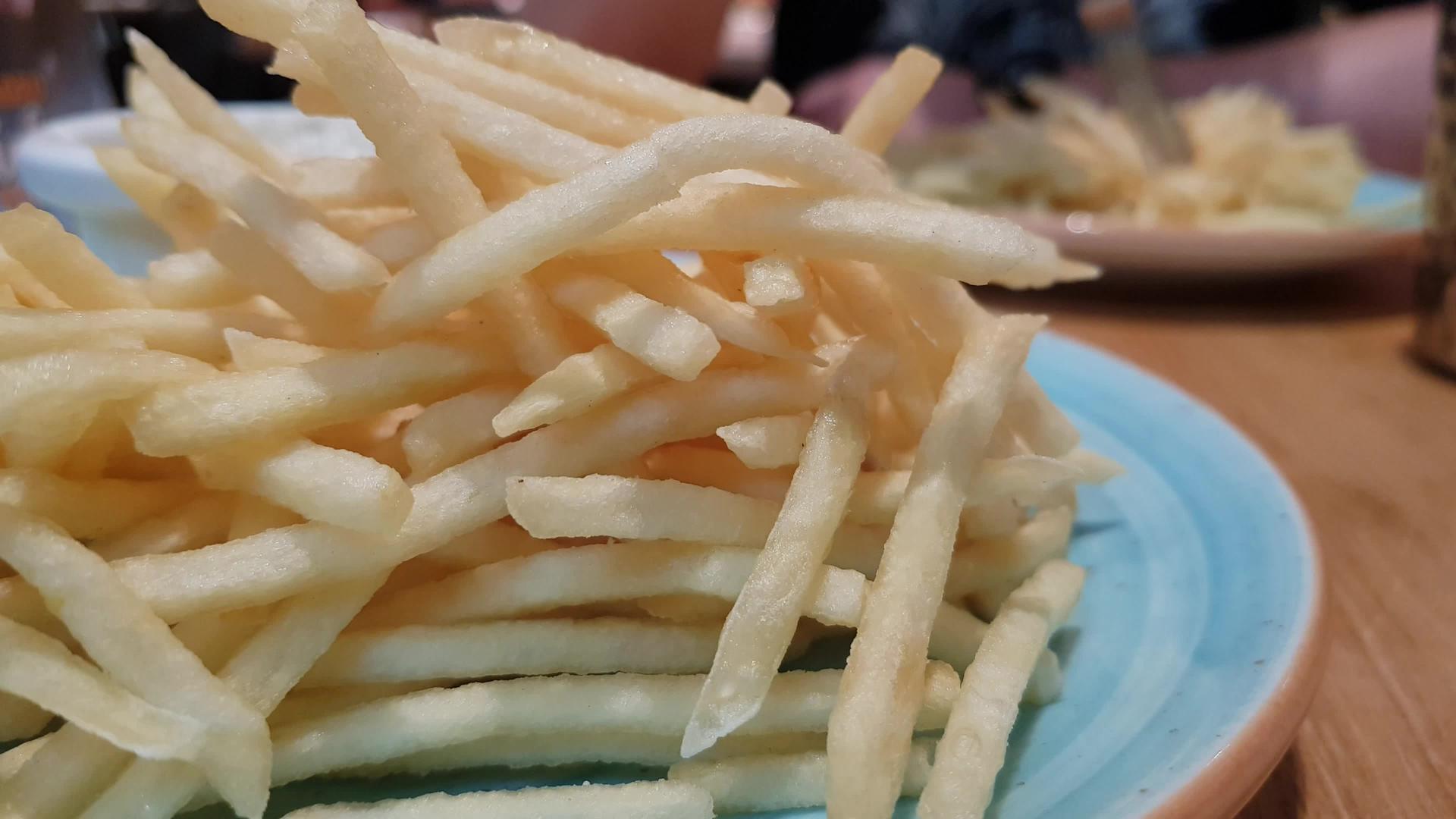 餐厅的蓝色盘子上有很多炸薯条专注的人用叉子吃薯条视频的预览图