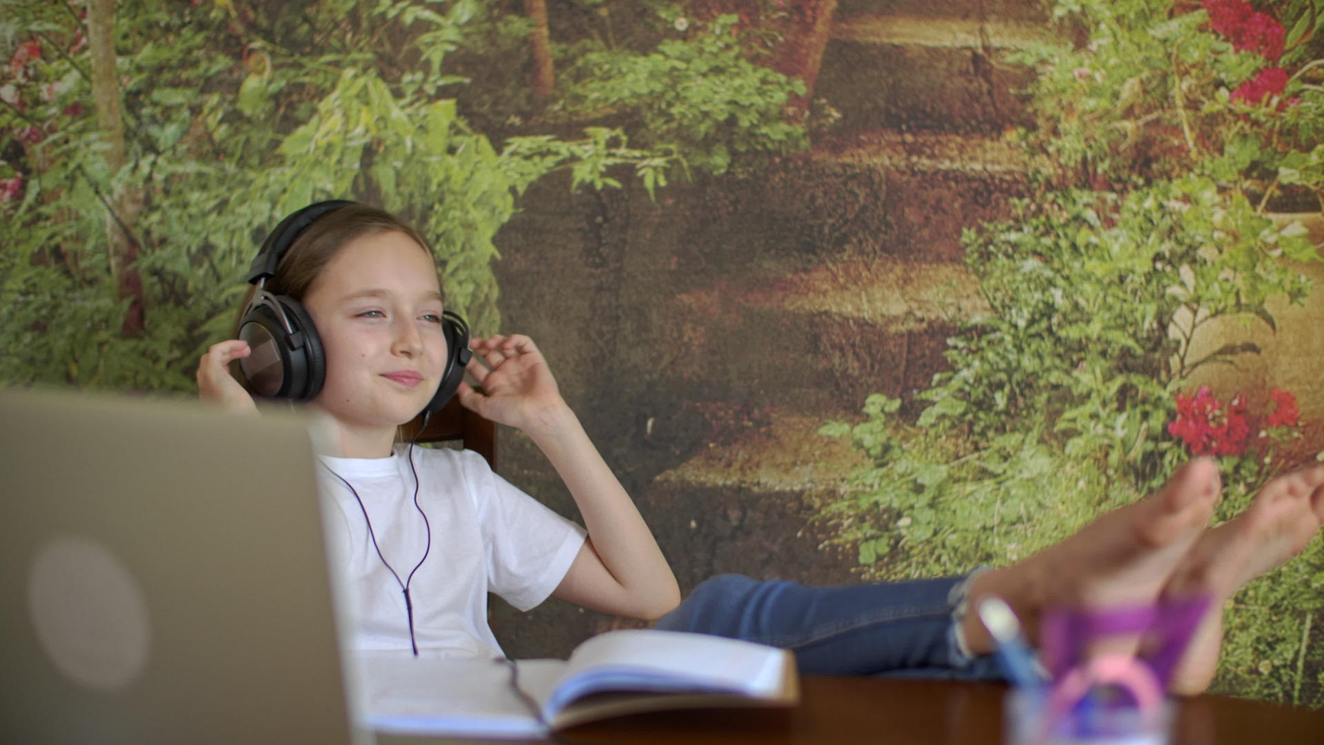 十几岁的女孩在家里用耳机听音乐无忧无虑的女孩把腿放在家里视频的预览图
