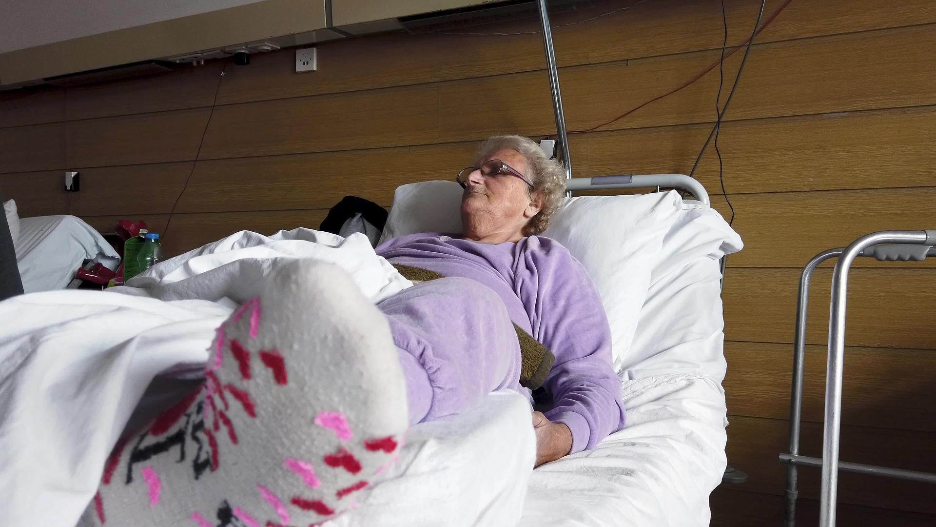 孤独的老年妇女沉浸在医院病房的白床单上视频的预览图