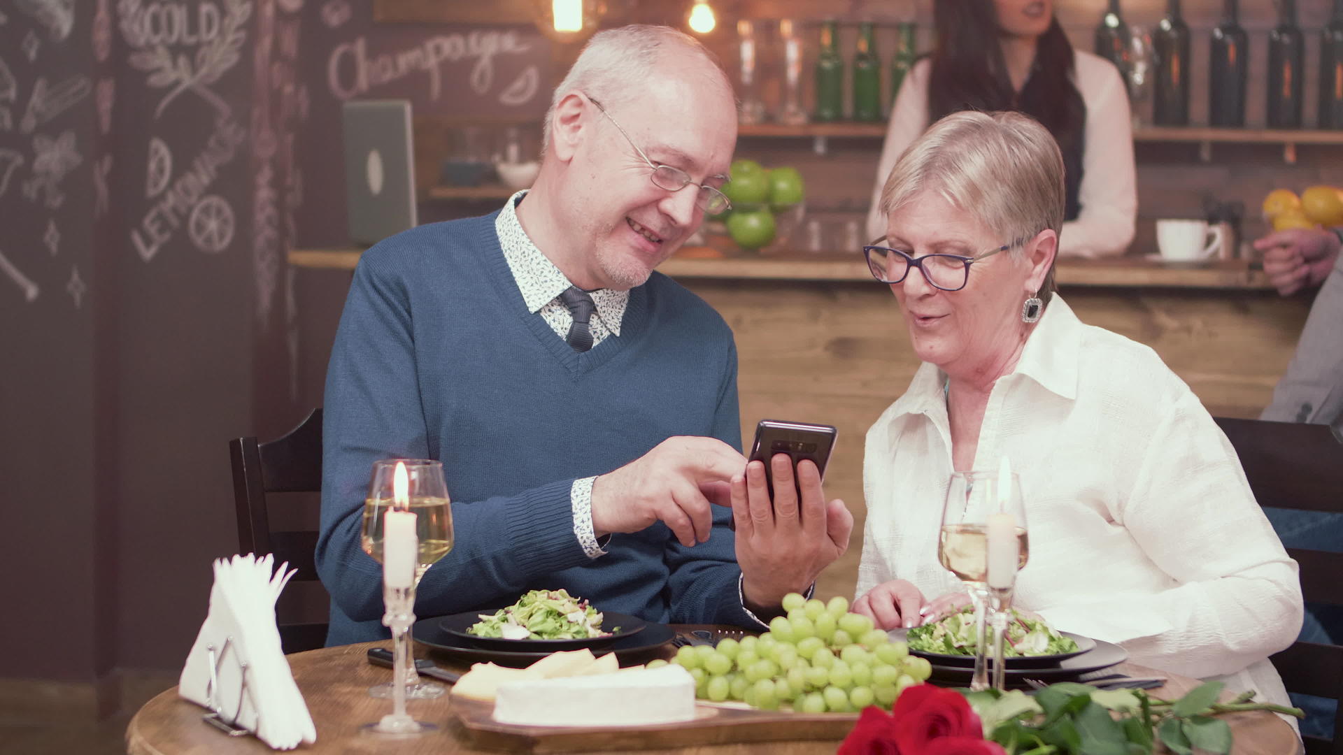 一对美丽的老夫妇在一家古董餐厅约会看着智能手机上的照片视频的预览图