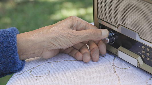 在后院的旧收音机上高级女性用手转动手柄视频的预览图