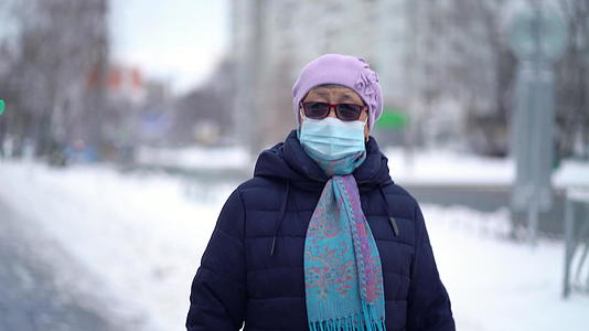 戴着医用口罩的老年妇女正在街上行走视频的预览图