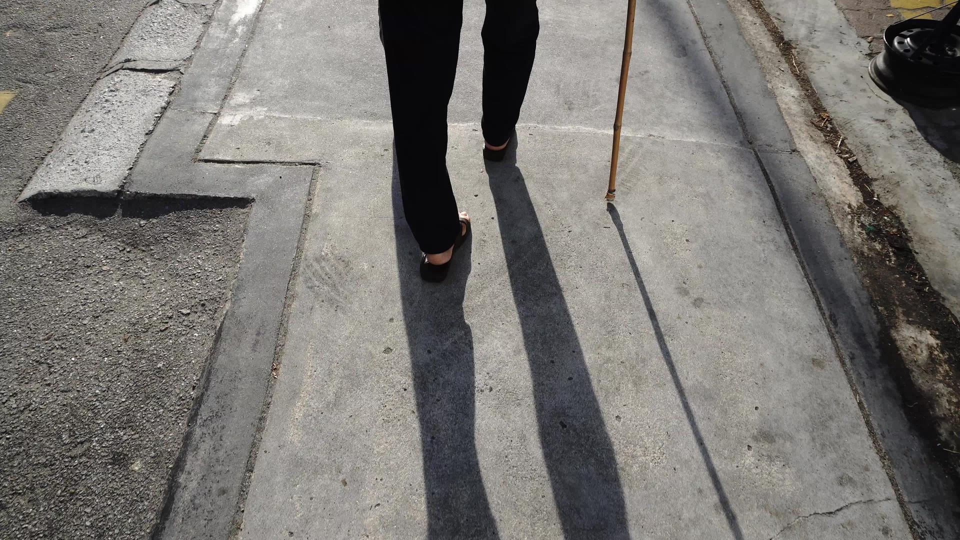 残疾妇女用扶手棍走路的背面视图视频的预览图