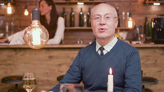 一位英俊的老人的肖像在酒吧里对着镜头说话视频的预览图