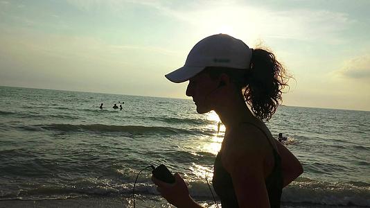 这位身材苗条、戴着帽子的年轻女子在日出时在海上从事体操活动视频的预览图