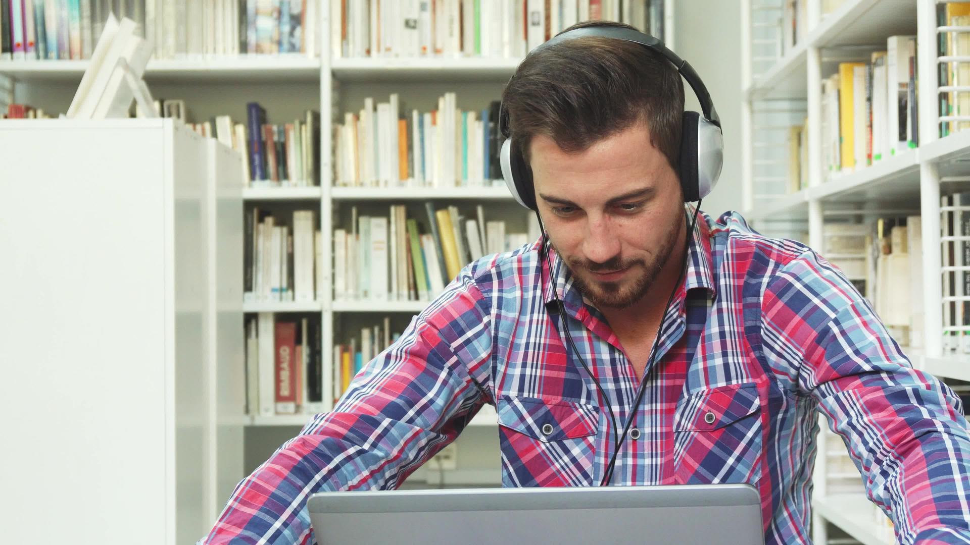 年轻人在笔记本电脑上听耳机音乐视频的预览图