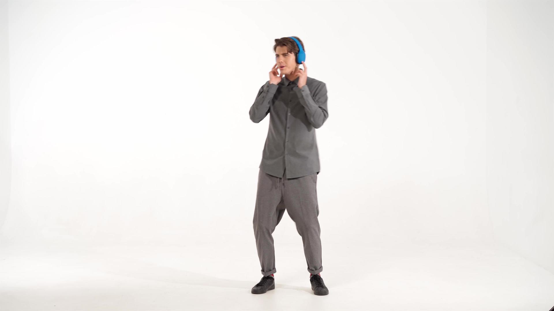 年轻人穿着灰色运动服戴着蓝色无线耳机听音乐视频的预览图