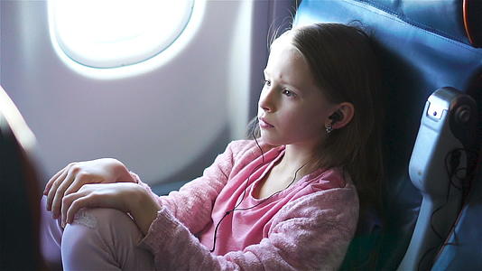 可爱的小女孩在飞机上旅行可爱的孩子坐在飞机的窗户附近视频的预览图