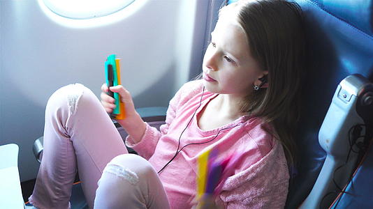 可爱的小女孩乘飞机旅行可爱的孩子膝盖电脑靠近飞机视频的预览图