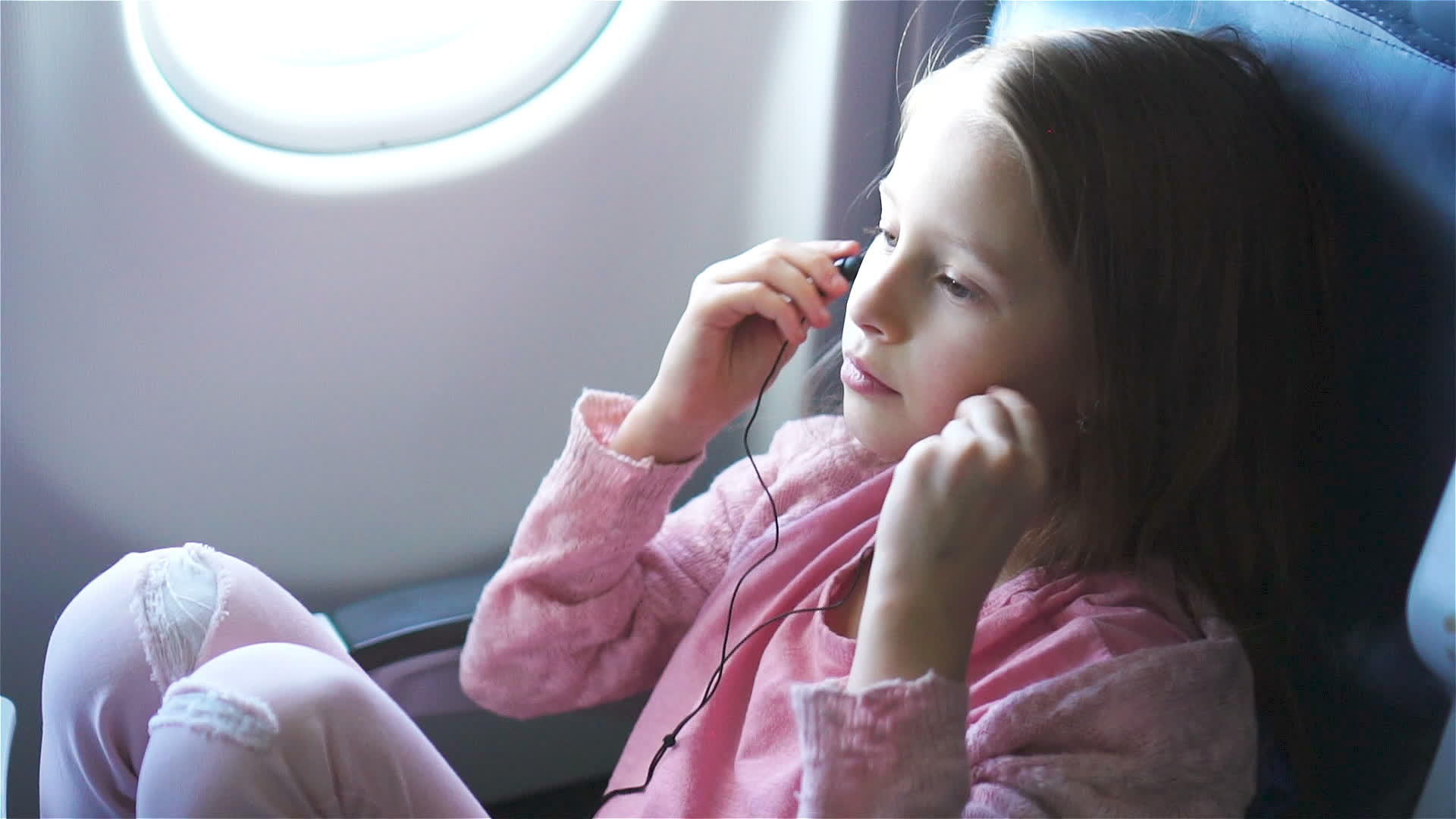可爱的小女孩在飞机上旅行可爱的孩子在飞机的窗户附近看着视频的预览图