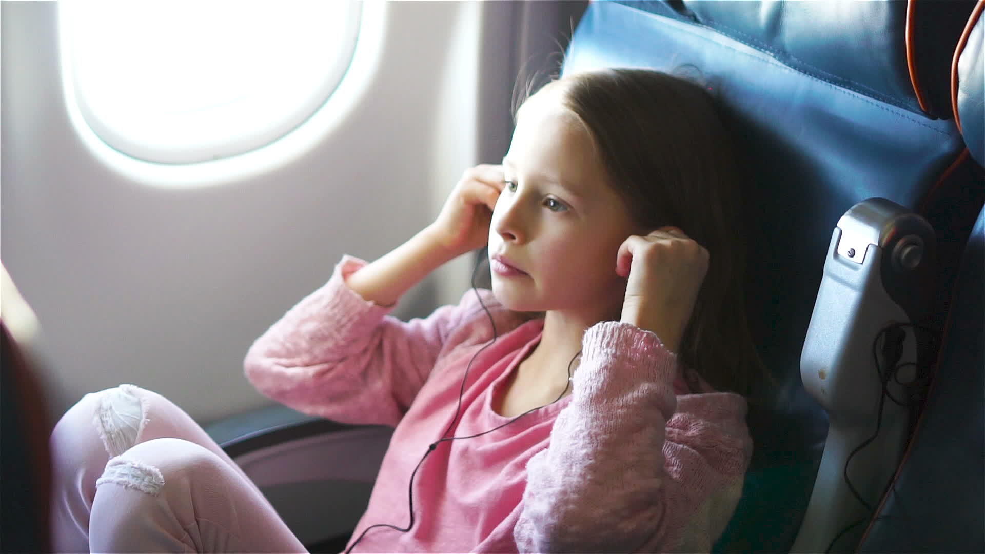 可爱的小女孩在飞机上旅行可爱的孩子在飞机窗附近听音乐视频的预览图