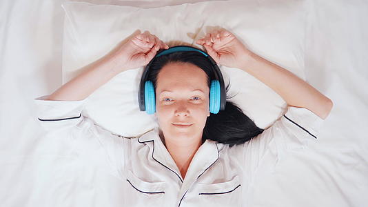 欢乐的caucasian棕发美女在床上听一首歌视频的预览图