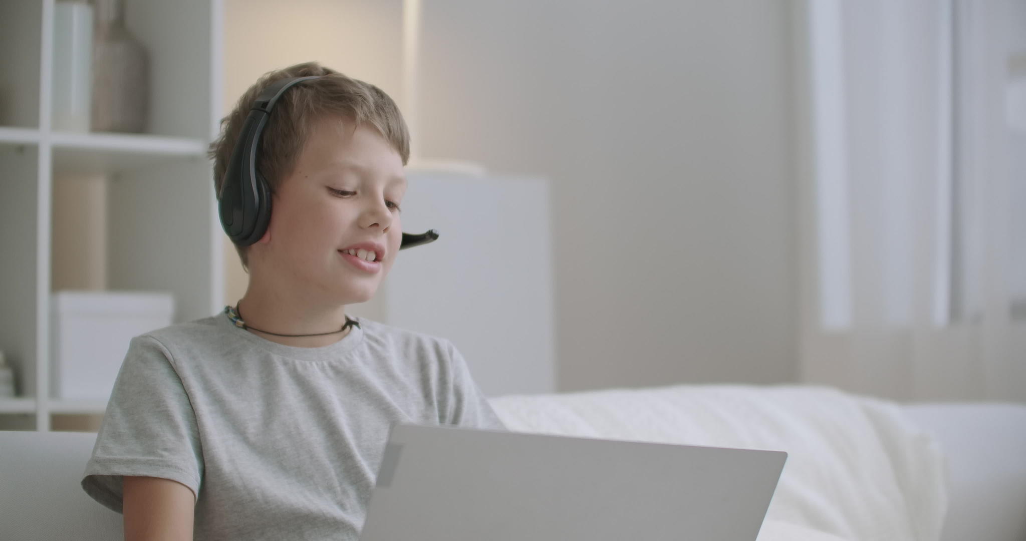 可爱的小男孩正在用笔记本电脑通过网络与朋友聊天视频的预览图