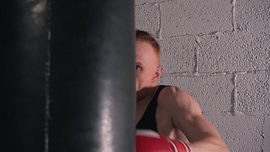 肌肉发达的拳击手戴着拳击手套踢在白砖墙的背景上视频的预览图