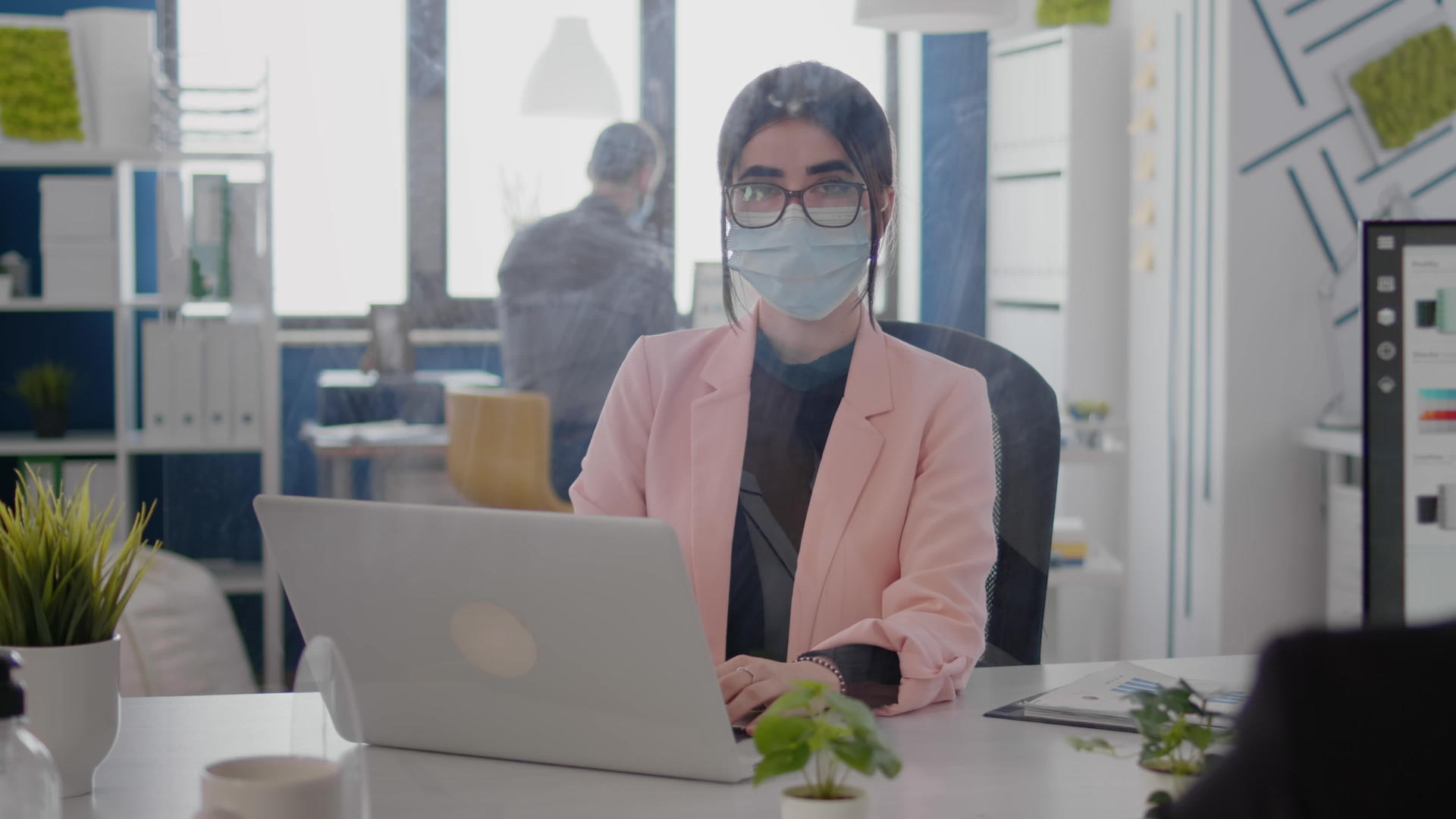 在笔记本电脑上工作的带有保护口罩的女商人肖像照片视频的预览图