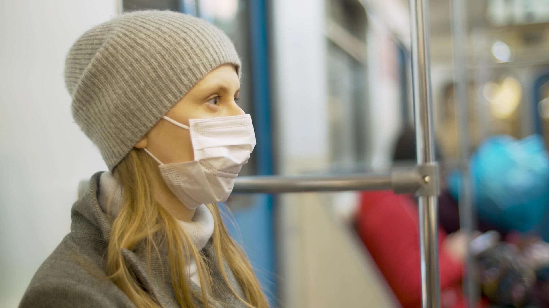 戴着面具的女人坐在地铁车厢里视频的预览图