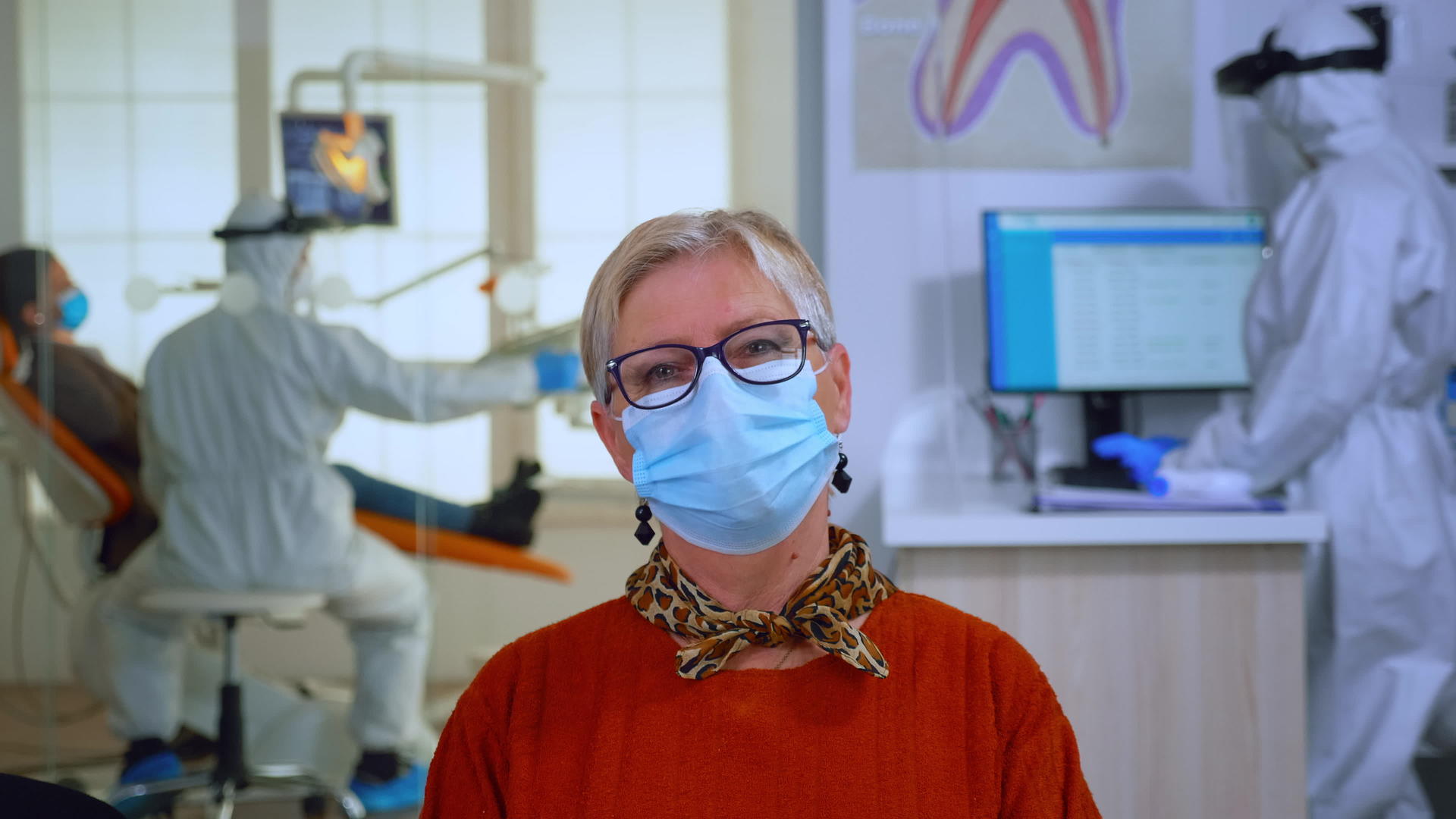 牙科办公室戴着口罩观看退休患者的肖像照片视频的预览图