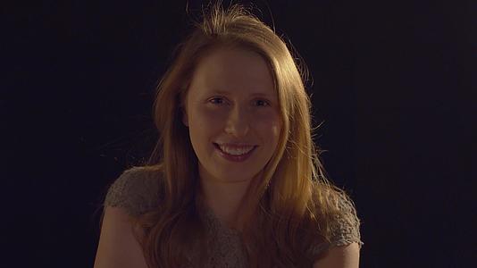 一个金发年轻女子的黑暗背景肖像视频的预览图