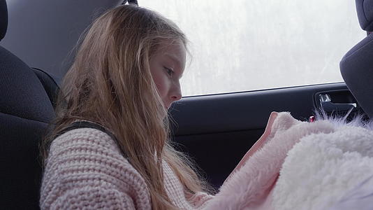 使用智能手机的肖像女孩在汽车轮廓后座旅行时使用智能手机视频的预览图