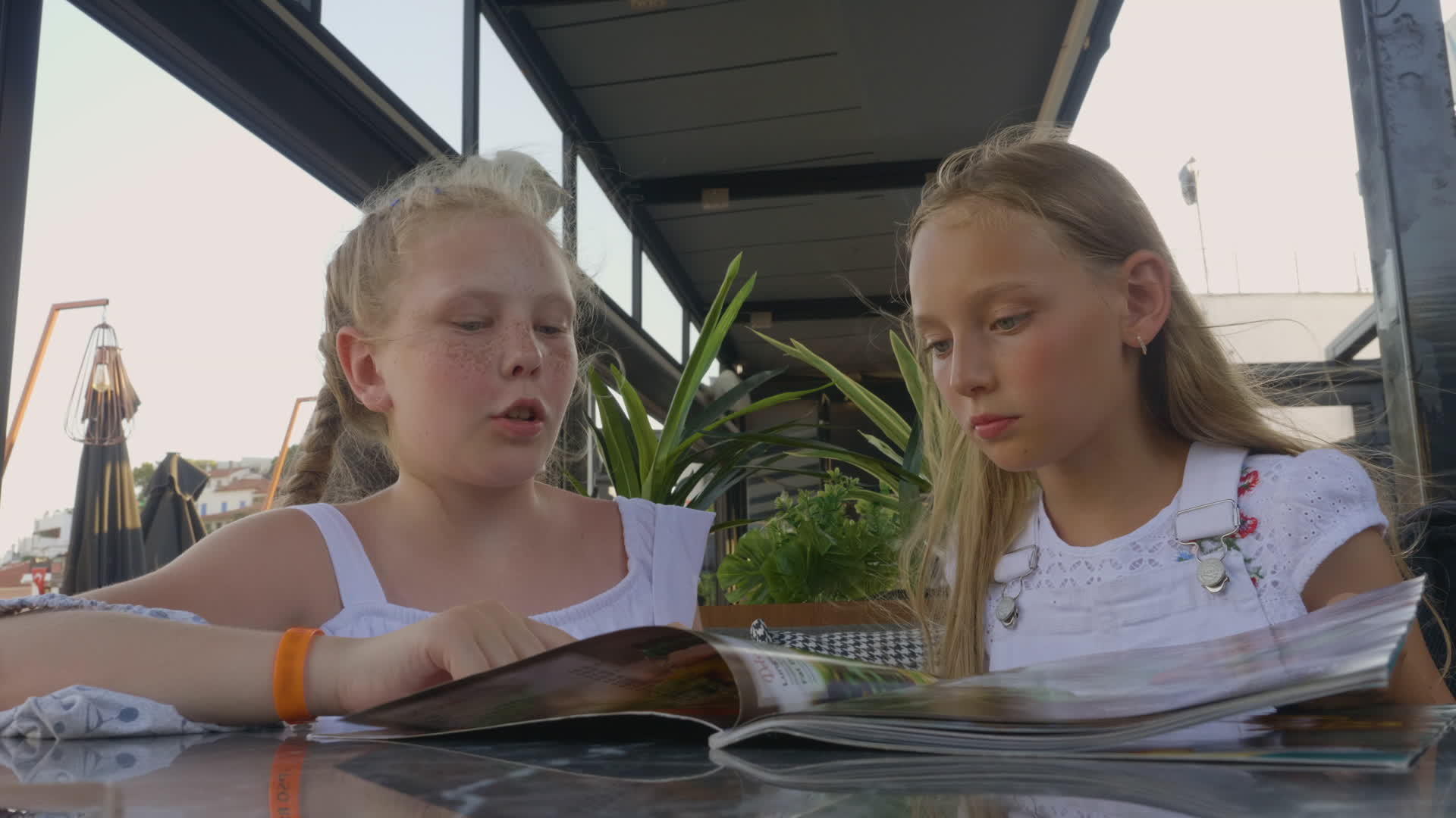 两个女孩在户外夏季咖啡馆看菜单年轻女孩在餐厅视频的预览图
