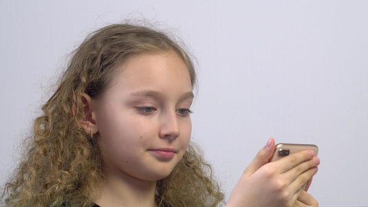 在手机上浏览社交网络的女孩微笑着面对快乐的卷发女孩视频的预览图