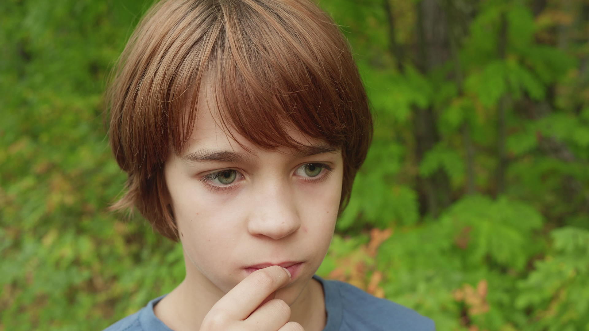 英俊的年轻男孩在户外嚼口香糖青树的背景下视频的预览图