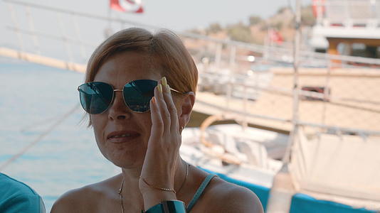 成年女性在海上行走的船上留着短发和太阳镜的肖像视频的预览图
