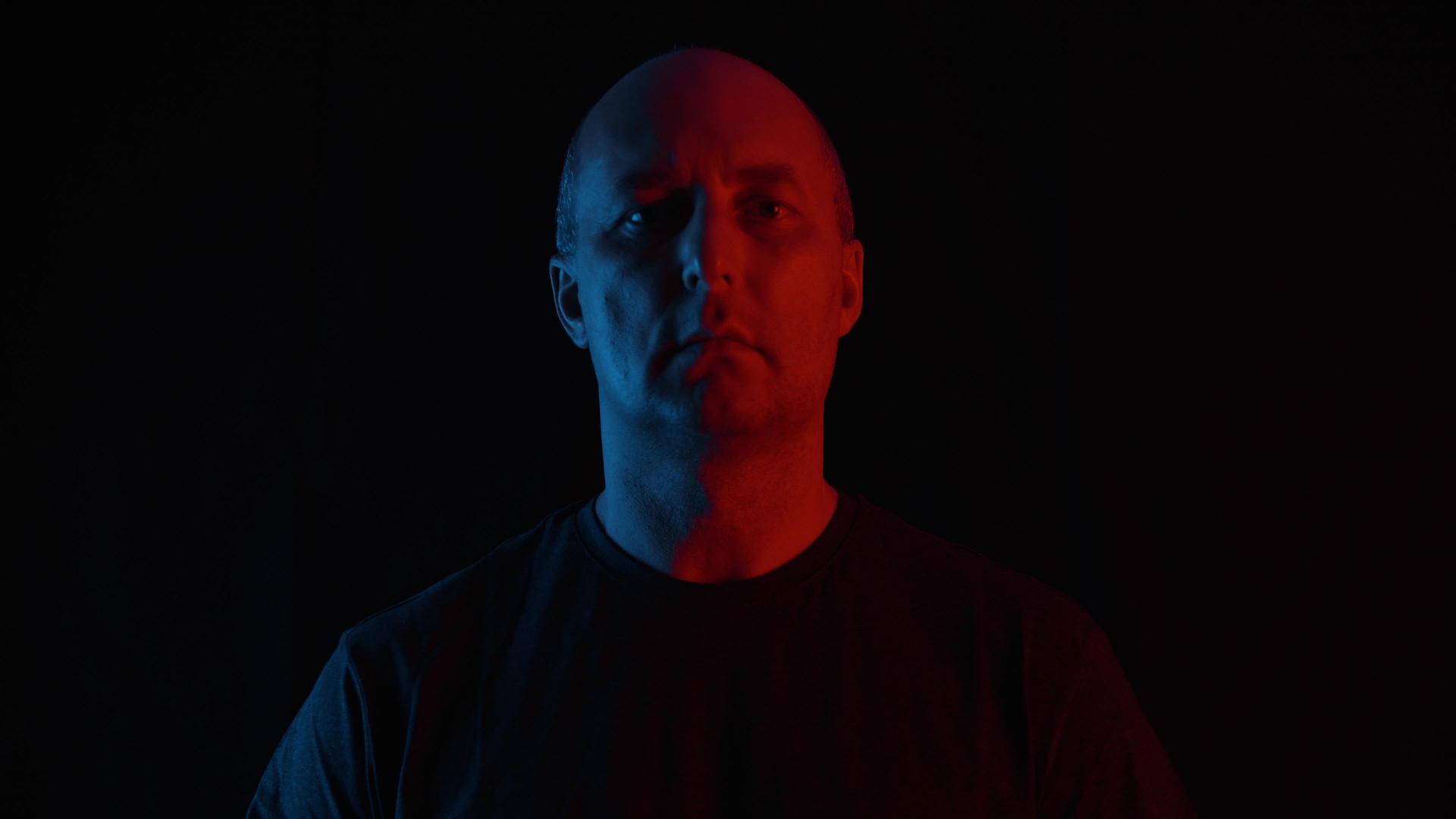 在蓝色和红色的灯光下黑色背景上的肖像在黑暗中视频的预览图