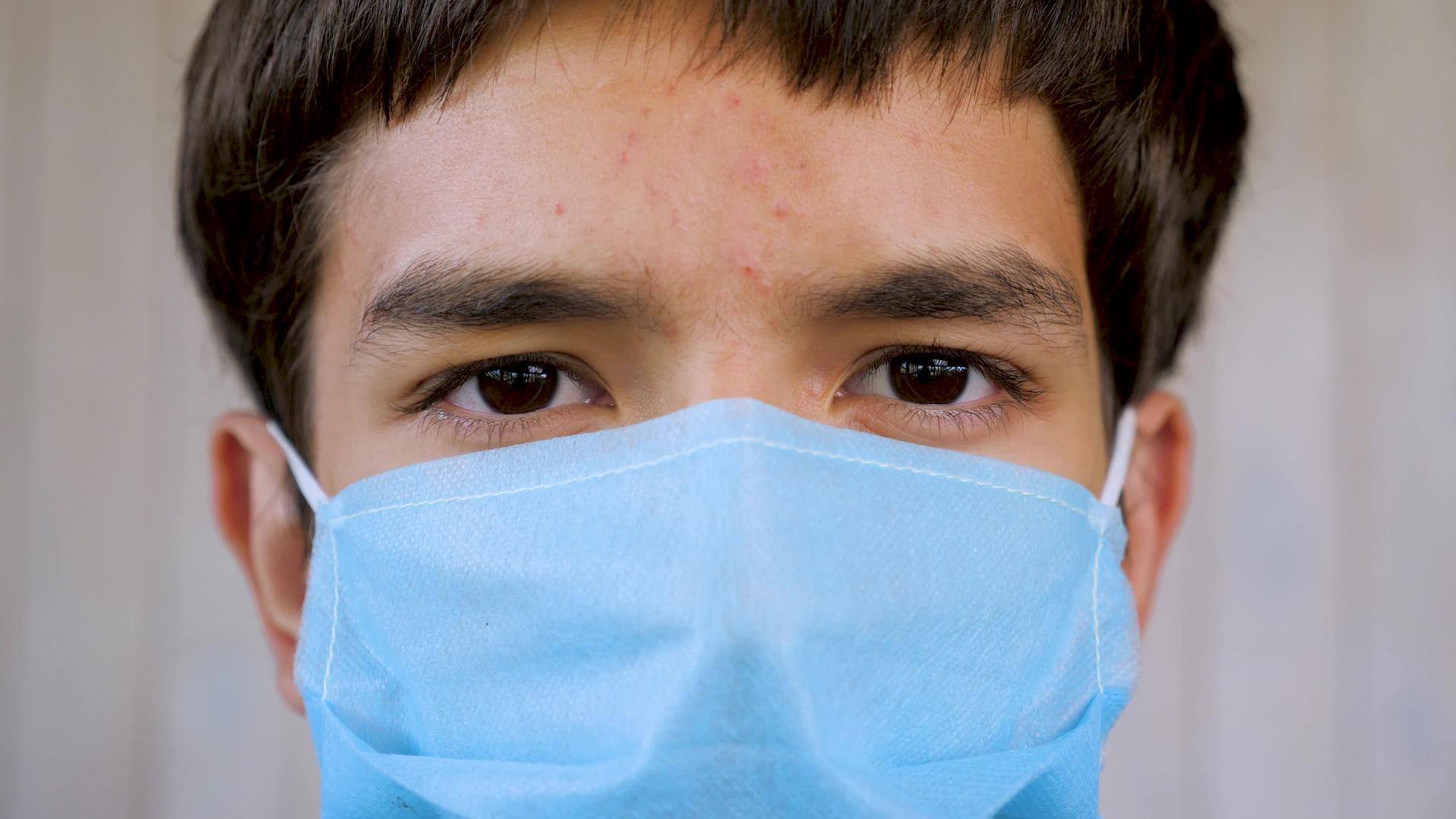 戴着蓝色医用口罩的年轻人看着镜头的特写镜头戴着防护口罩的病人视频的预览图