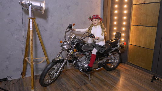 一个年轻漂亮的女孩的工作室坐在摩托车上戴着摩托车戴着帽子视频的预览图