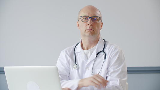 男医生点头坐在医疗办公室的桌子前视频的预览图