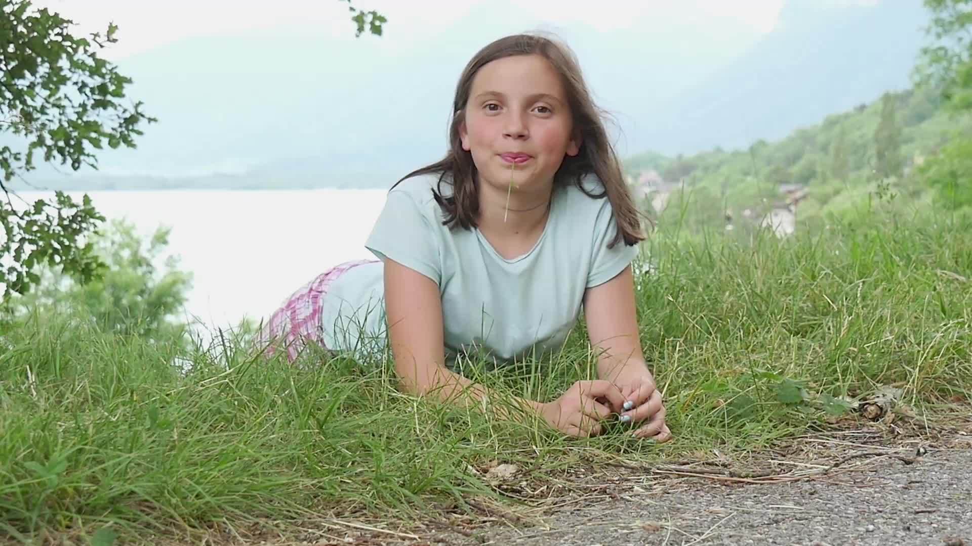 年轻漂亮的女孩躺在草地上慢慢地动作视频的预览图
