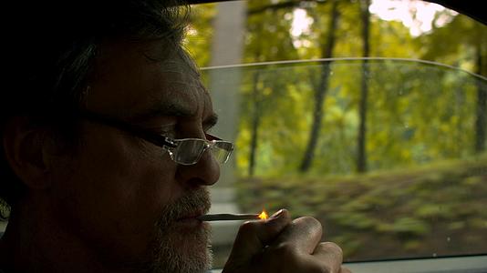 驾驶汽车和吸烟的高级男子肖像视频的预览图