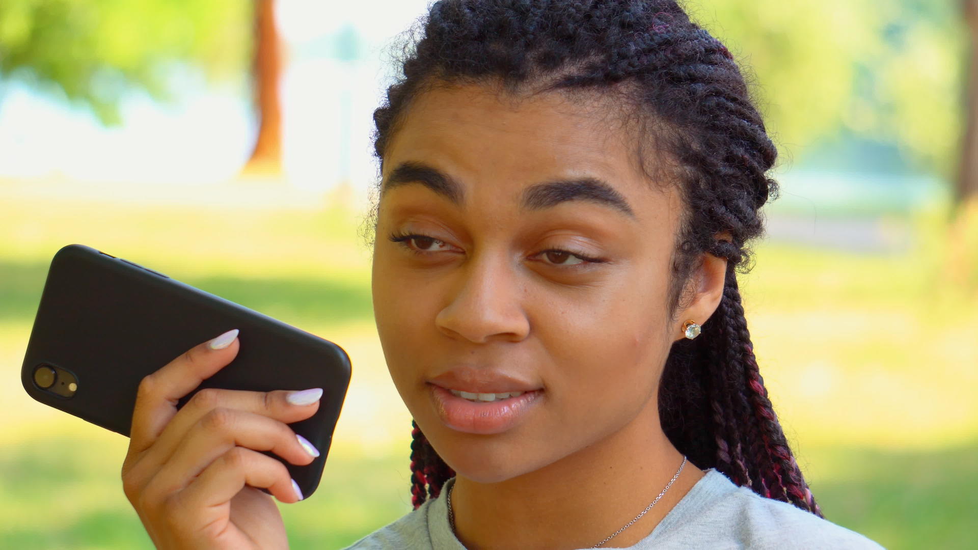 女孩在公园里用手机发送语音信息视频的预览图