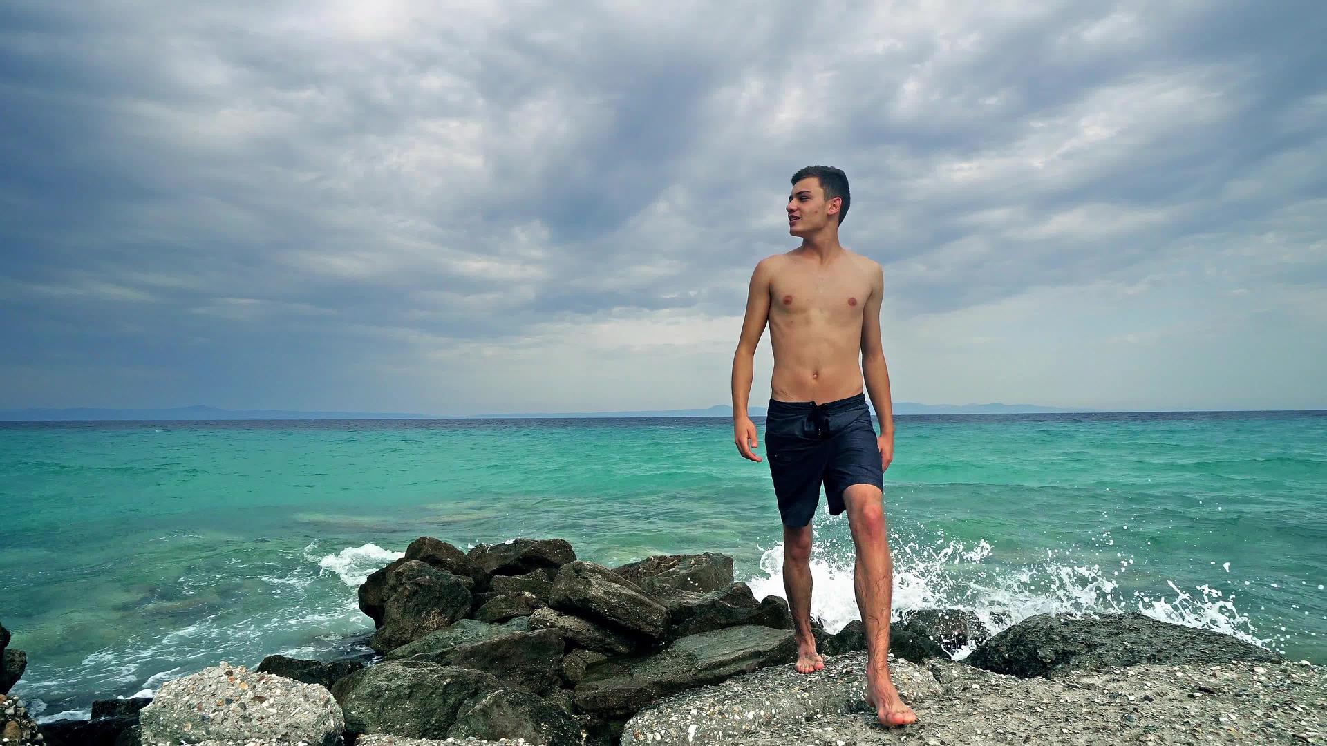 快乐的年轻健康青少年在岩石上行走在海洋前享受假期视频的预览图