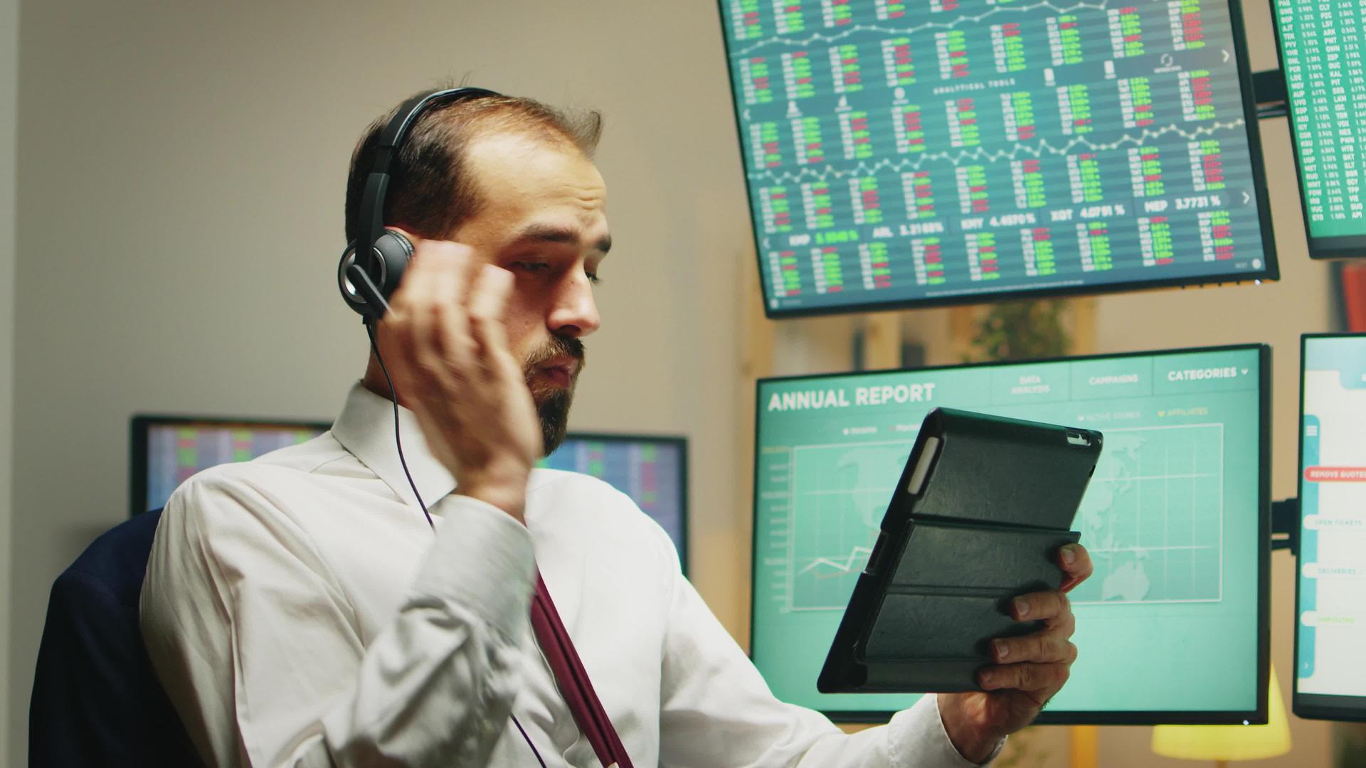 市场股票经纪人在使用平板电脑时用耳机交谈视频的预览图