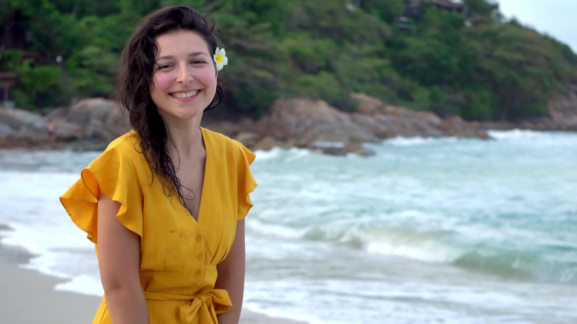 一个穿着黄色连衣裙的年轻漂亮的黑发女孩在海湾边缘视频的预览图