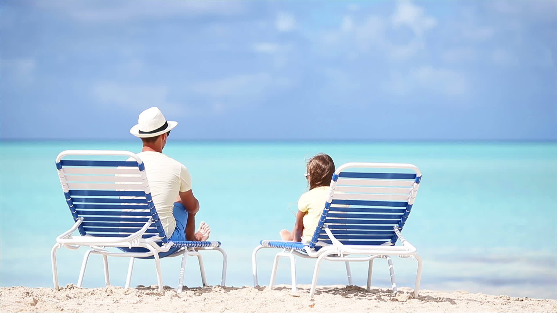 小女孩和她年幼的父亲坐在海滩上享受她的假期视频的预览图