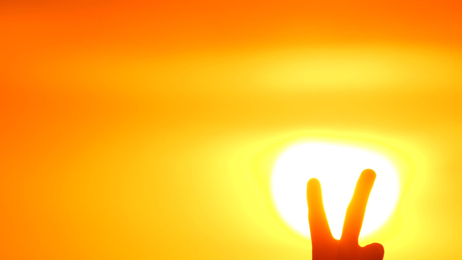 V在美丽的橙色日落或日出背景下人们展示了胜利的标志视频的预览图