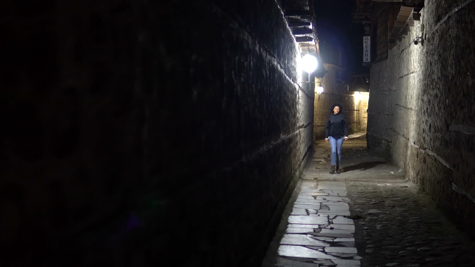 晚上孤独的女人走在后街的旧石路上视频的预览图