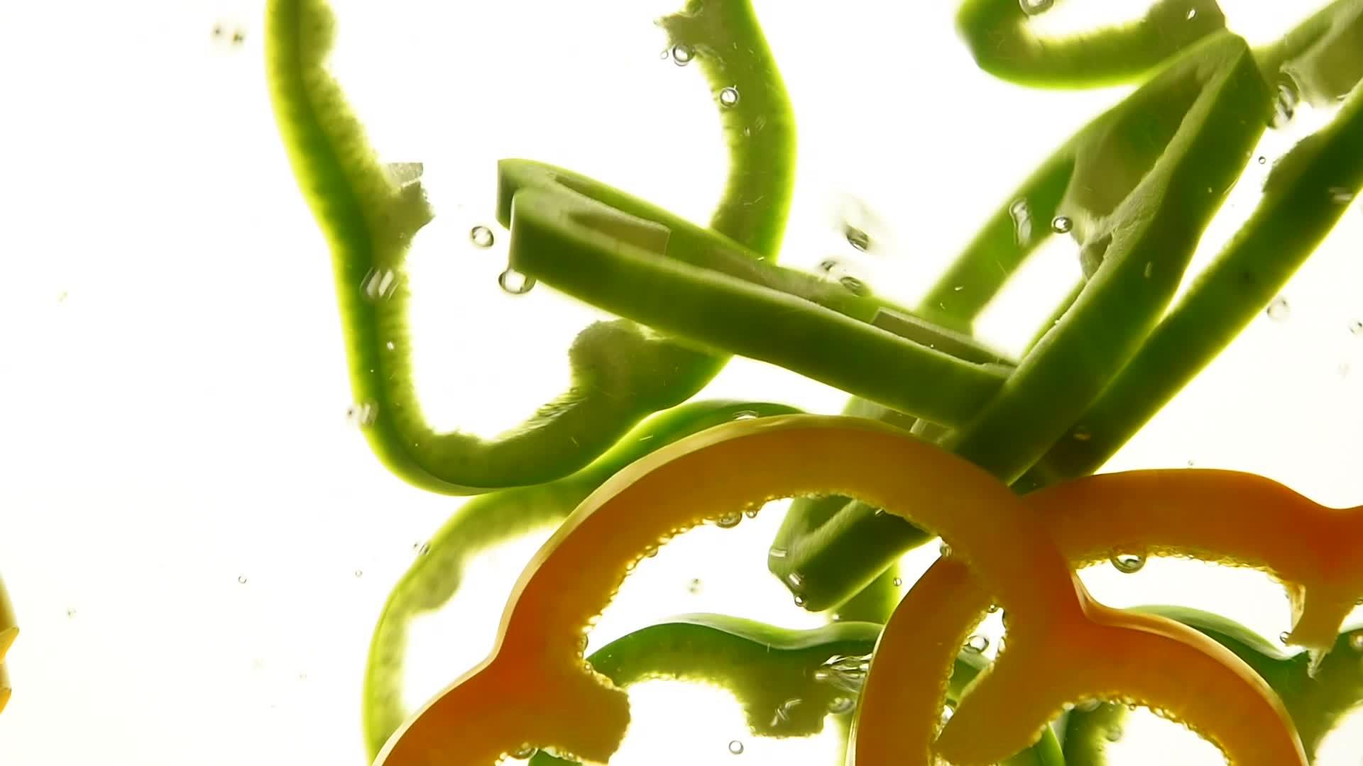 黄色和绿色的胡椒在水中漂浮视频的预览图