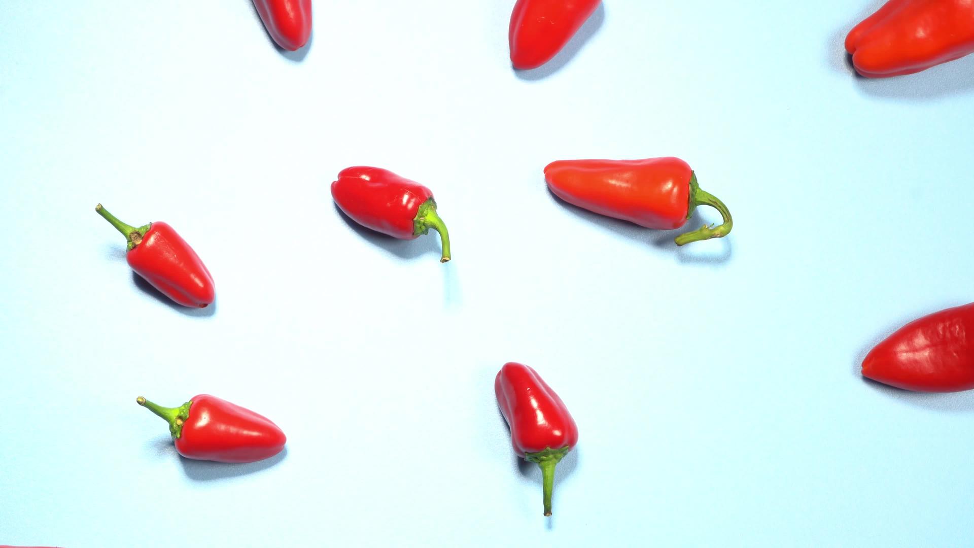 小红辣椒的顶视图混乱地散落在蓝色背景上视频的预览图